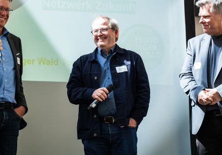 Drei Personen auf einer Bühne eines Events.