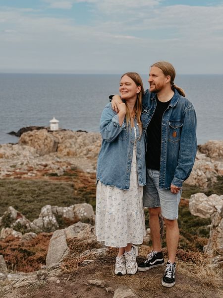 Britta und Sascha stehen an einer Klippe mit Meer im Hintergrund
