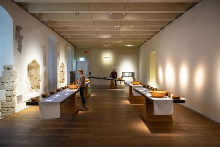Museumsausstellung mit zwei langen Holztischen, auf denen zahlreiche Keramikschalen präsentiert werden.