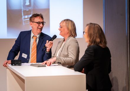 Ein Moderator im Gespräch mit zwei Frauen