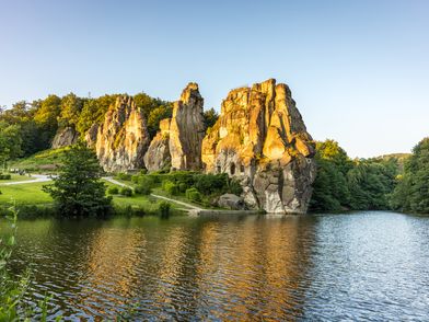 Zu sehen sind riesige Felsformationen, die sich in einem davor liegenden See spiegeln.