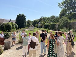 Eine Gruppe von Menschen, die in einem Klostergarten eine Führung erlebt.