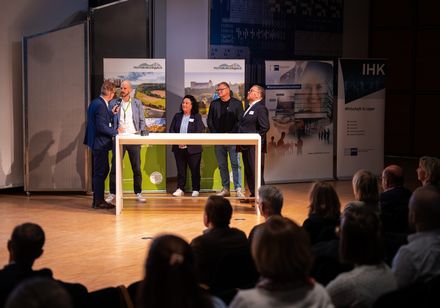 Ein Moderator im Gespräch mit einer Frau und drei Männern