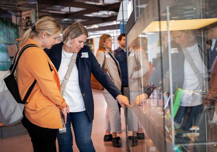 Zwei Frauen besuchen ein Museum, eine der beiden deutet auf ein Exponat.