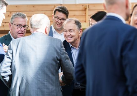 Ein Mann begrüßt eine Person auf einem Event.