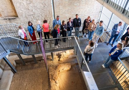 Besuchergruppe bei einer Führung über historische Ausgrabungen im Innenbereich.