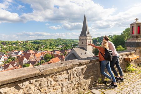 Illustration für Tourismuspartnerschaft - Paar an eine Mauer gelehnt blickt auf Warburg, Urlaubsregion Teutoburger Wald 