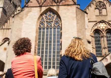 Zwei Frauen vor der imposanten Fassade einer historischen Kirche.