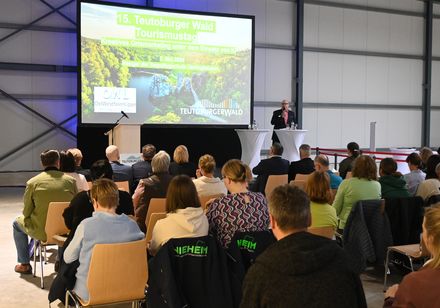 Ein Moderatür begrüßt das Publikum.