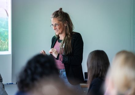 Eine Frau hält vor einer Gruppe von Menschen einen Vortrag.