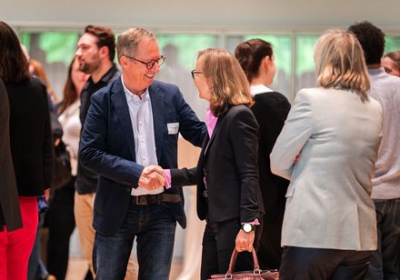 Ein Mann begrüßt eine Frau auf einer Veranstaltung.